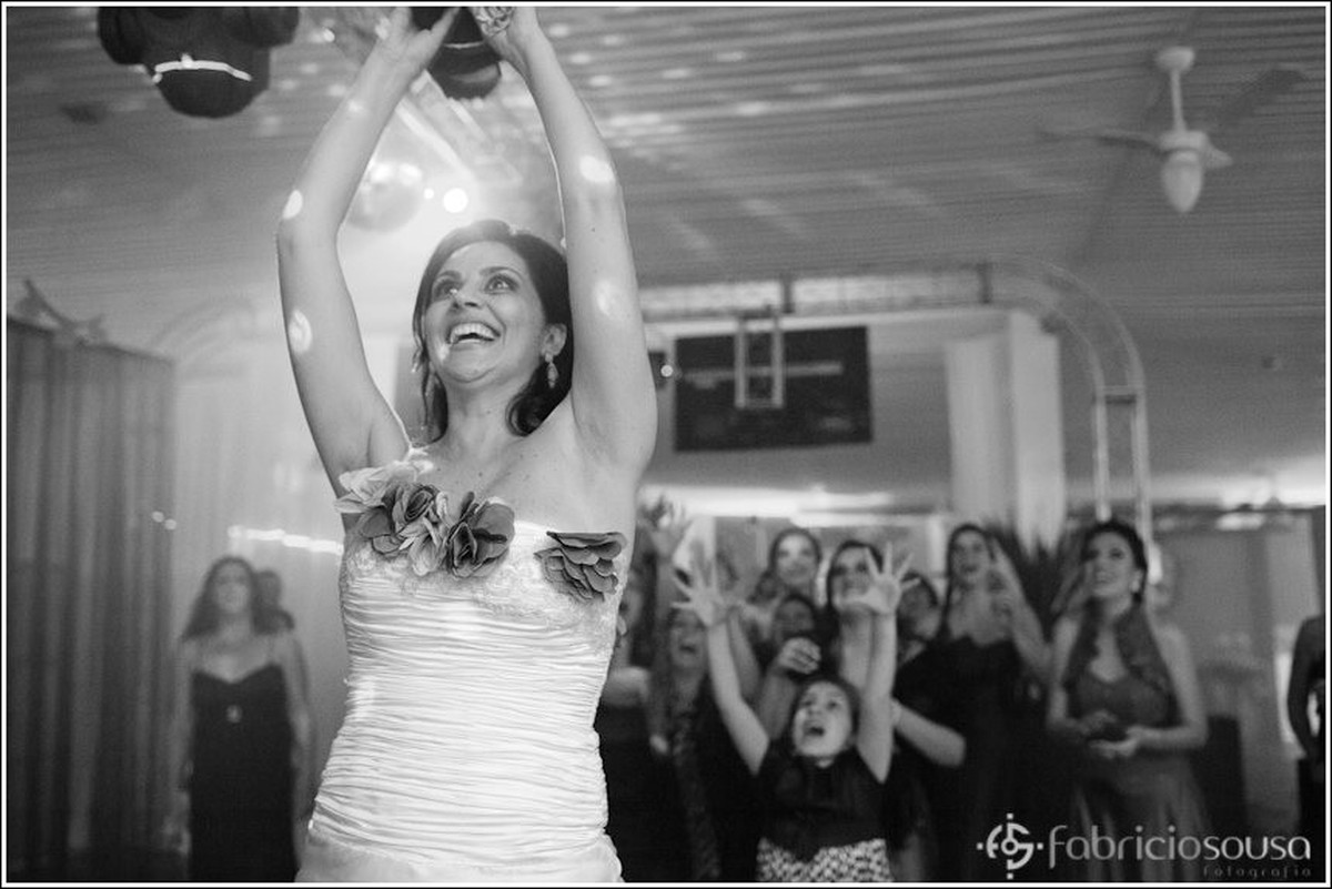 Noiva arremessando o bouquet e as moças com os braços pra cima