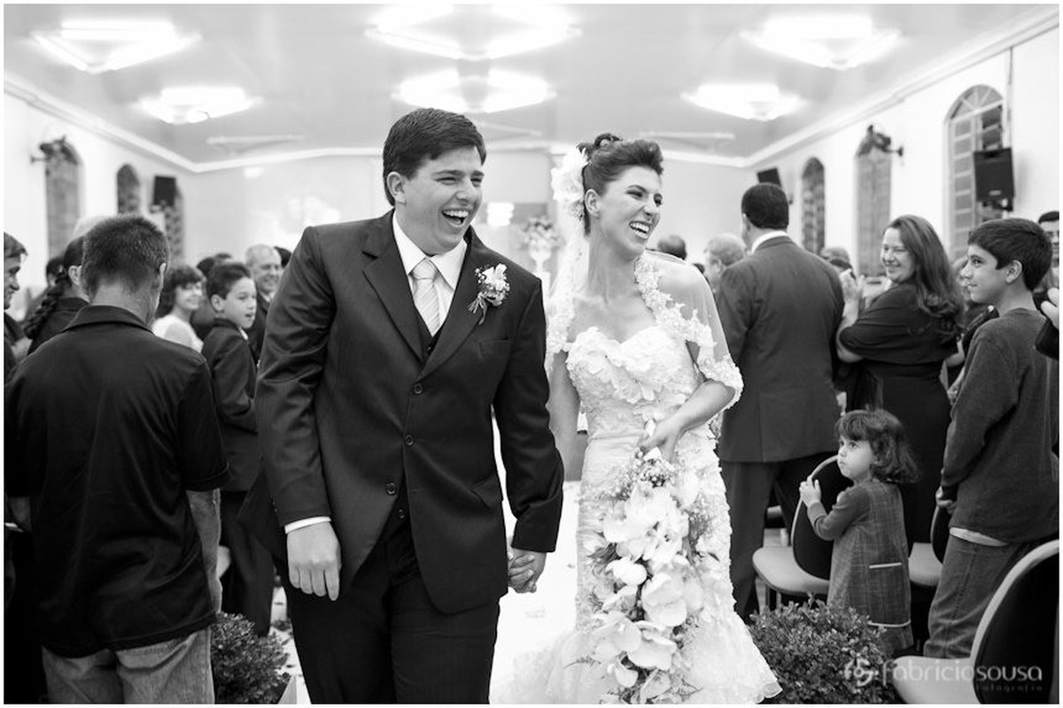 Casal de noivos sorriem alegres na saída da igreja