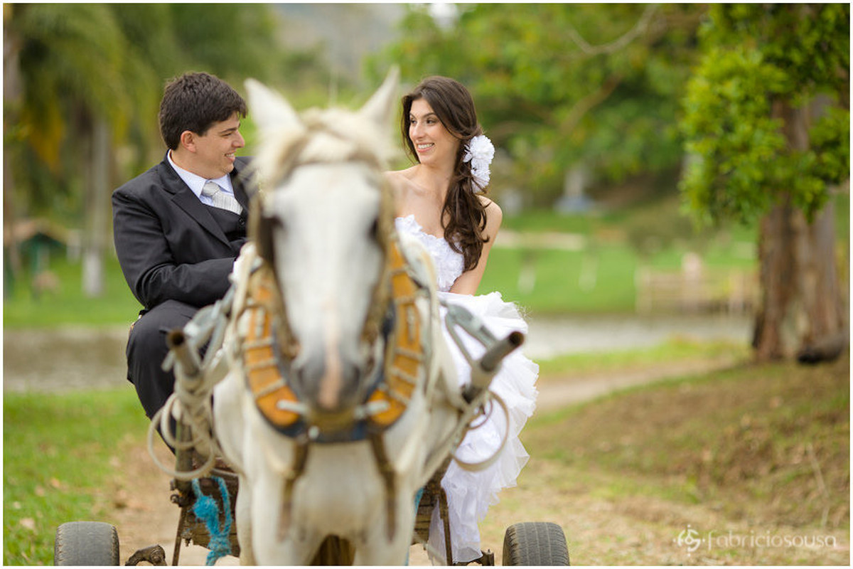 Noivo e noiva andam em charrete movida à cavalo