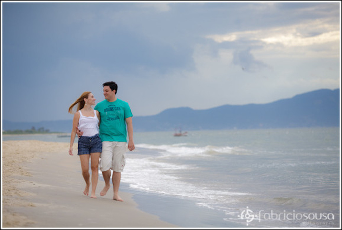 Casal de namorados caminham na beira do mar na praia