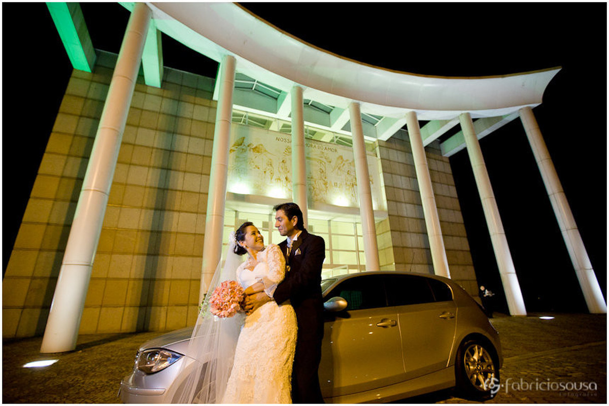 Recem casados posam junto ao carro