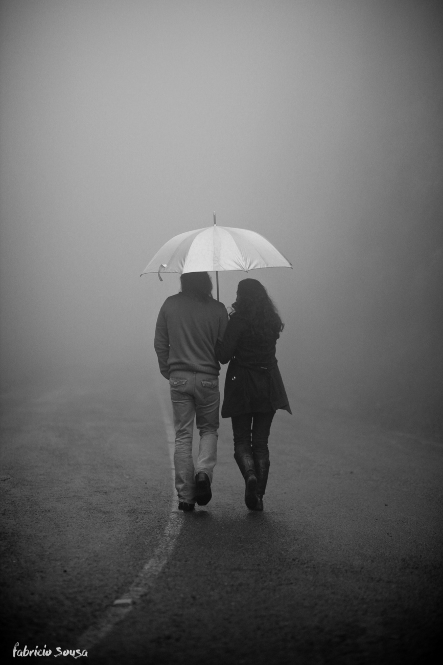 Casal de costas caminhando com guarda chuva