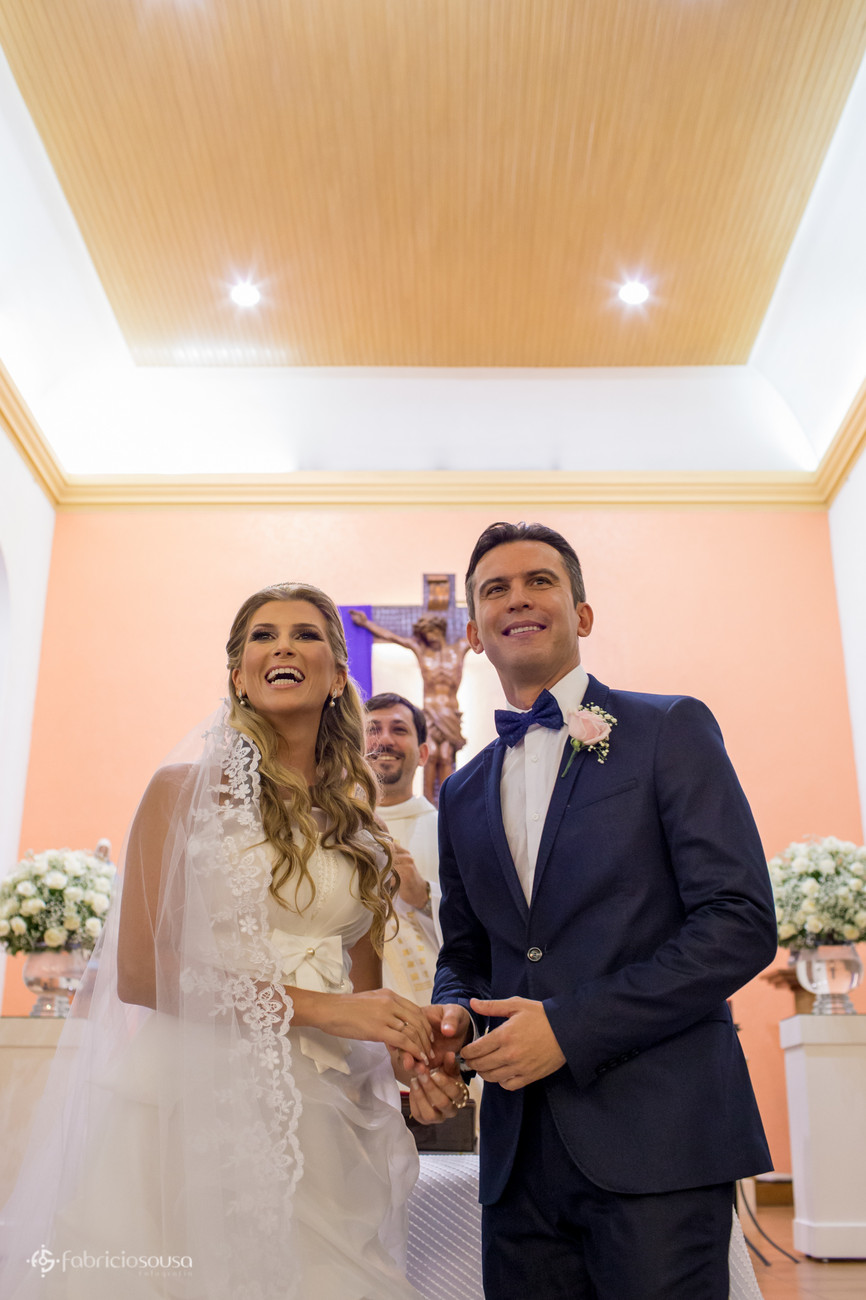 Casal de noivos no altar sorriem para os convidados presentes na igreja