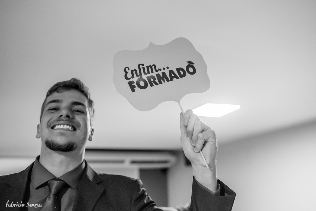 formando com sua placa "enfim... formado" durante seu jantar de formatura