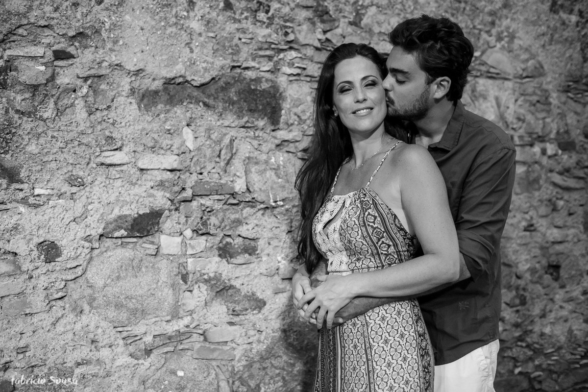 beijinho no rosto da noiva no ensaio pre-casamento em frente à muro de pedra