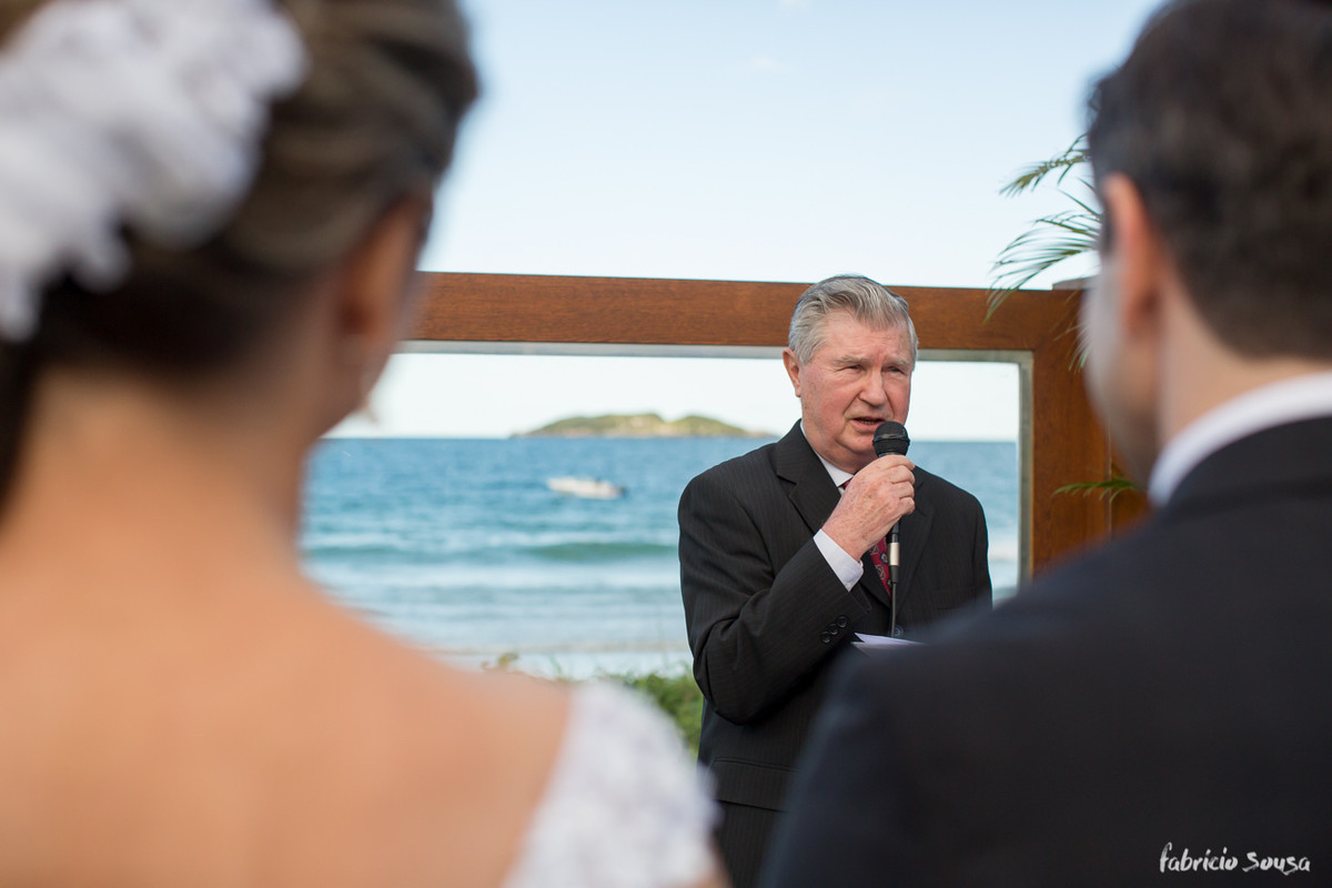 tio da noiva celebrando a cerimonia com o mar de fundo