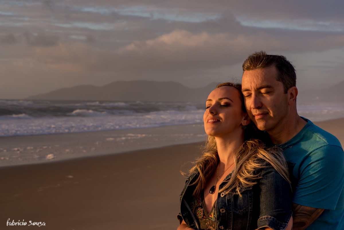 casal de olhos fechados sentindo os primeiros raios de sol do dia na praia do sul da ilha de Santa Catarina