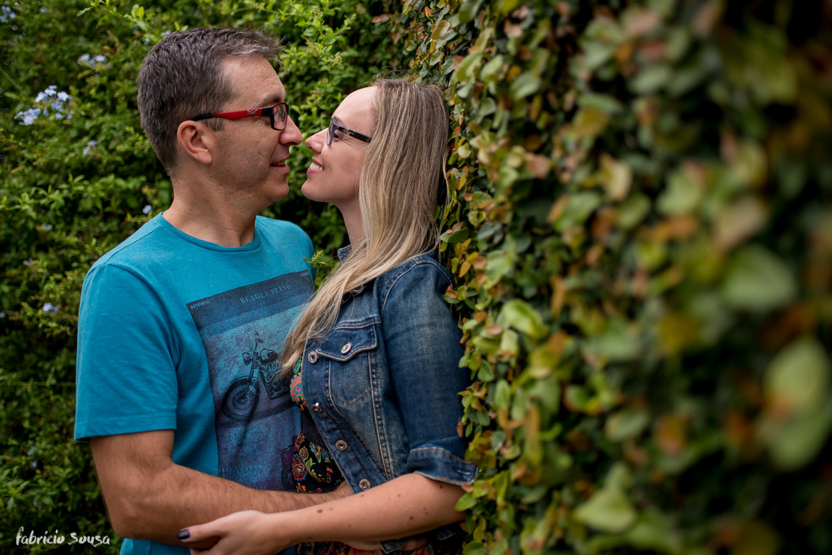 quase beijo do casal apoiado na cerca viva