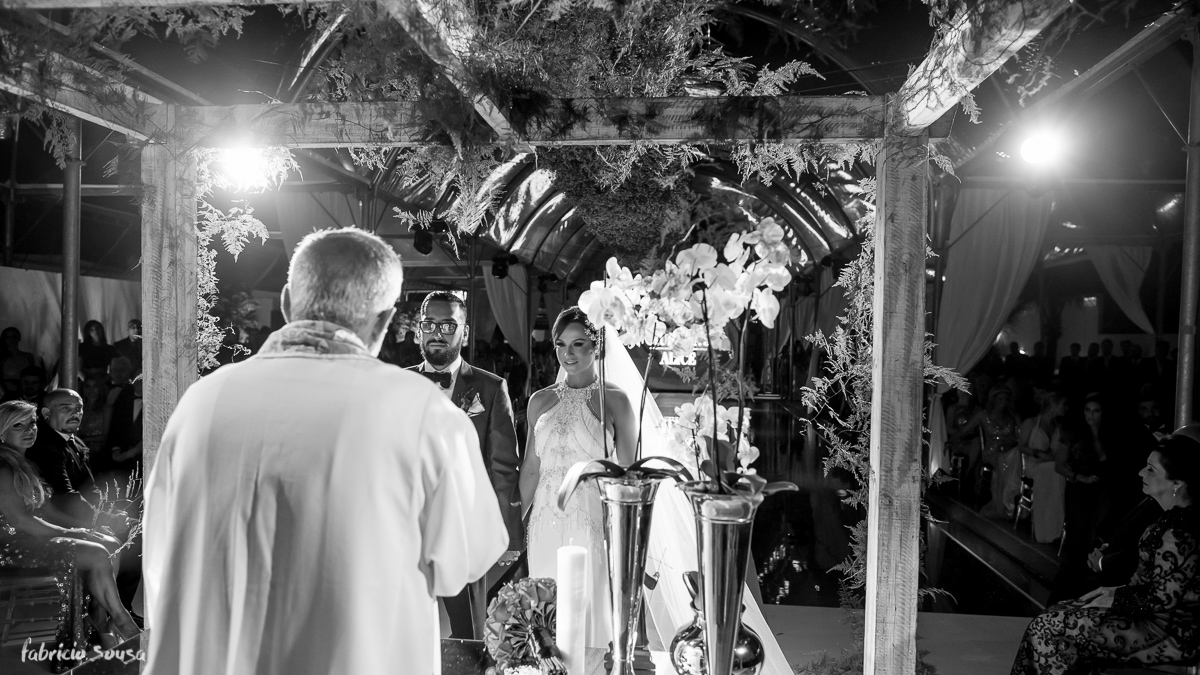 retrato preto e branco dos noivos no altar com orquídeas