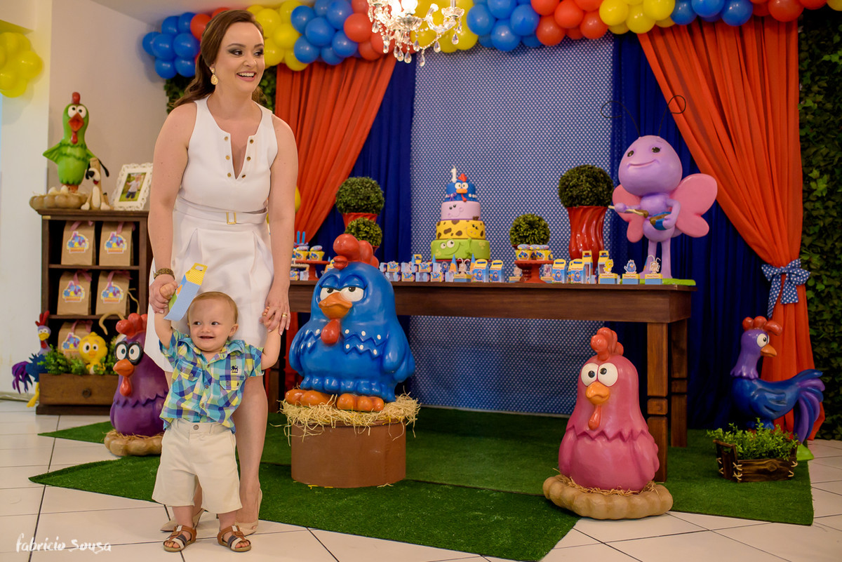 Mamãe com bebê sorridente em frente a sua decoracao de galinha pintadinha no primeiro aniversario