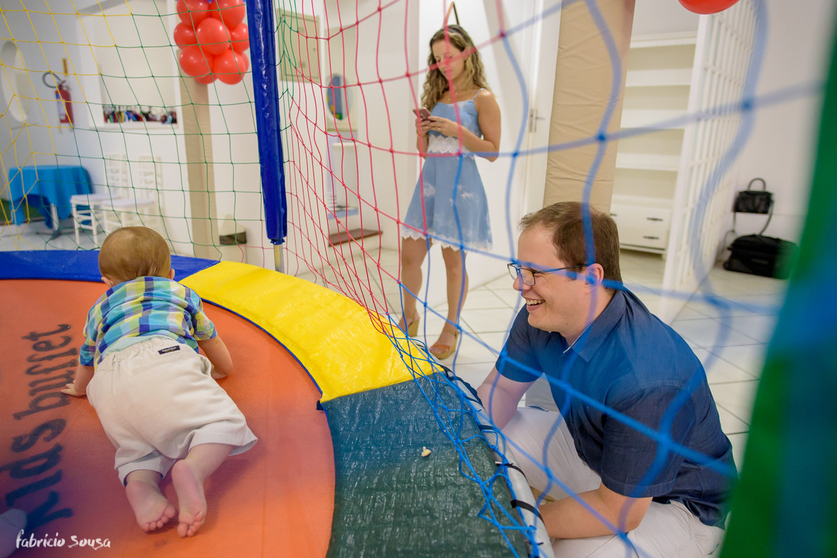 papai orgulhoso sorridente assiste filho brincando no pula-pula
