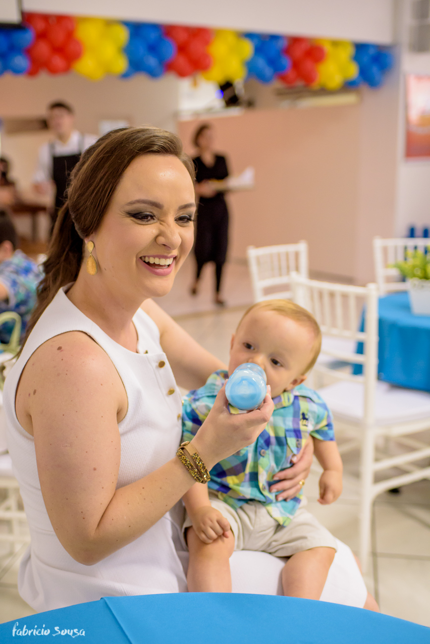 mamãe dá mamadeira pro filho durante seu primeiro aniversário