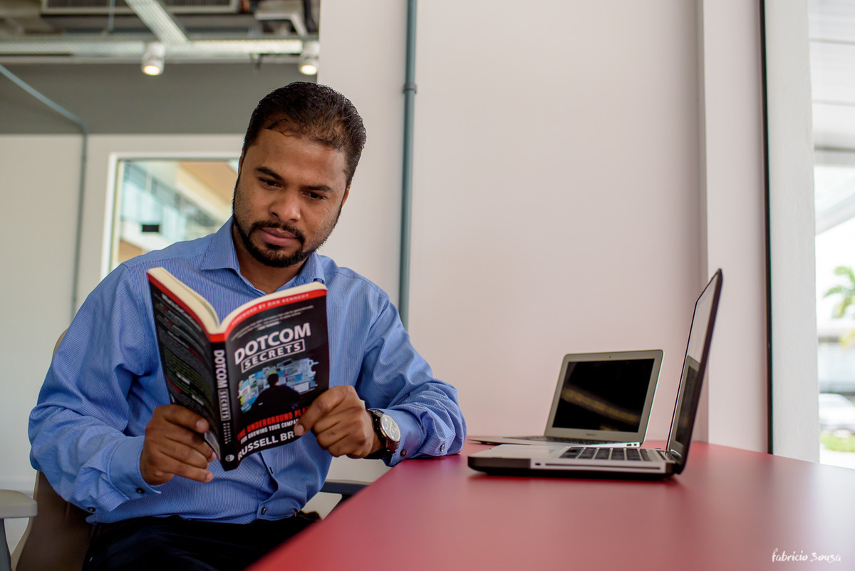empreendedor lendo livro na bancada de trabalho vermelha