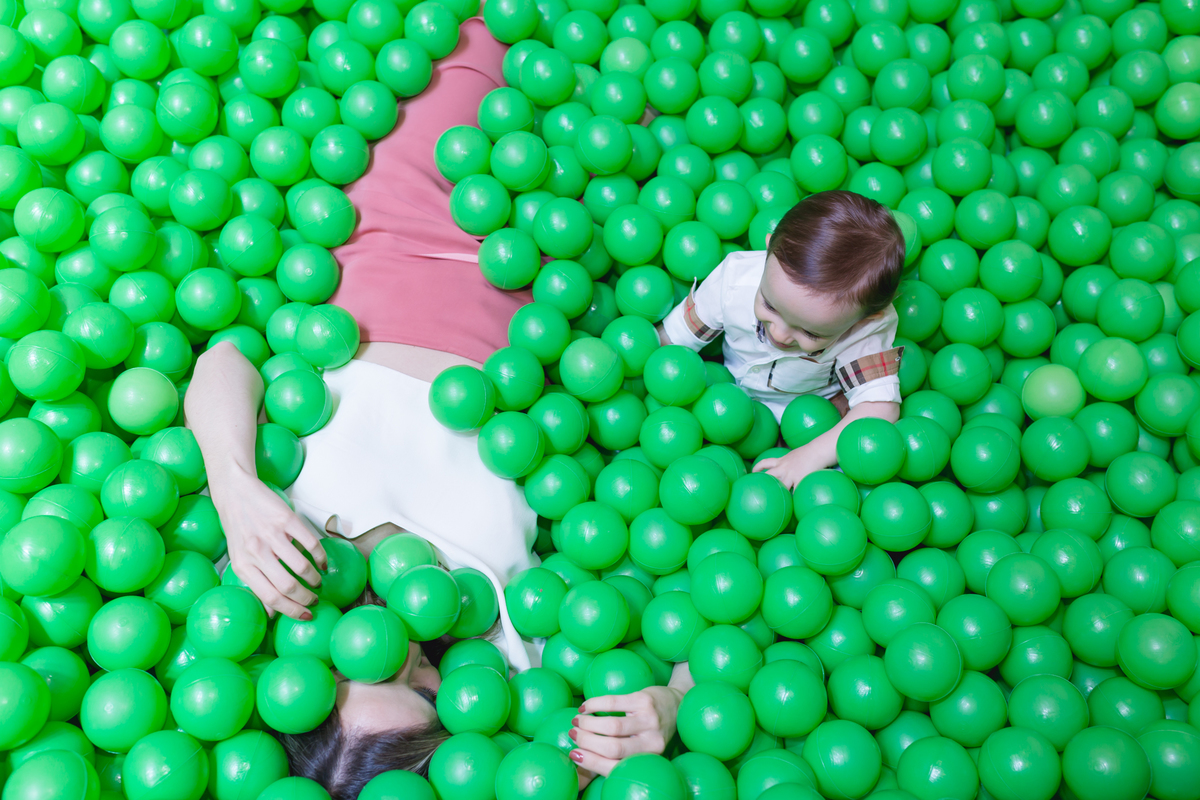 criança brincando com a mãe na piscina de bolinha