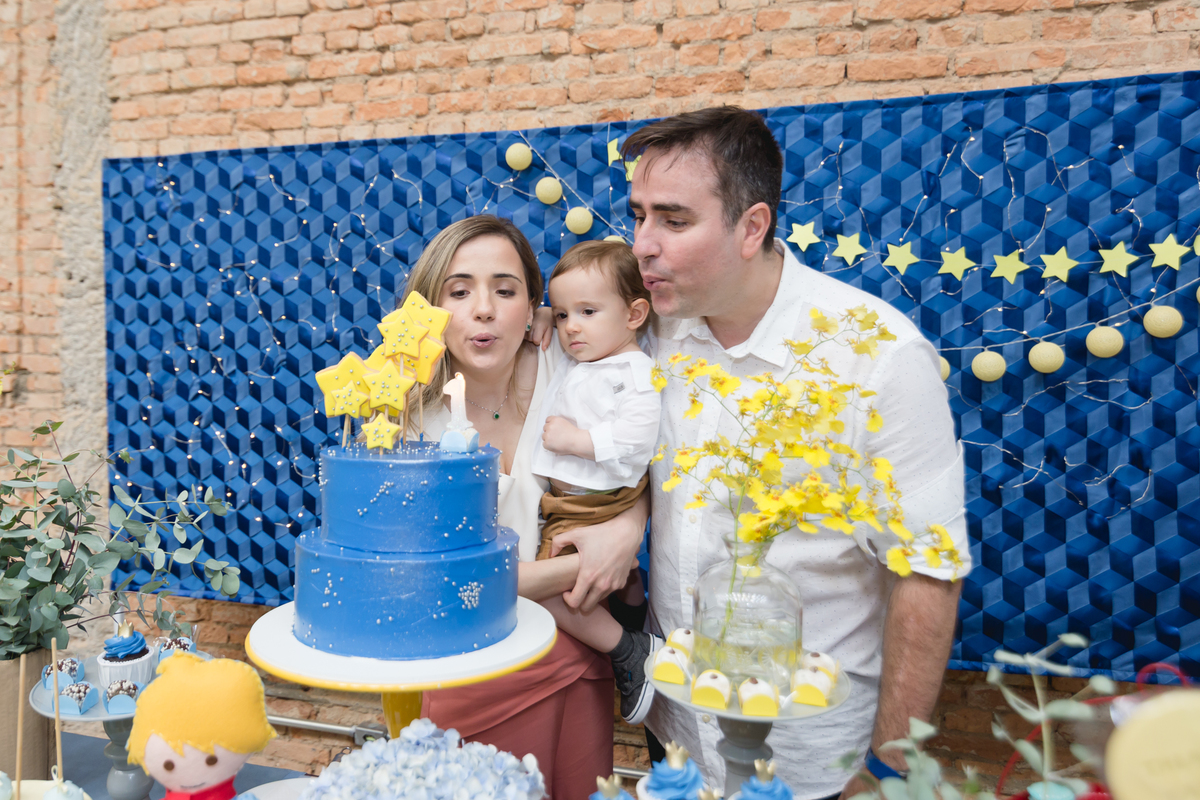 pais assoprando a vela com criança no colo