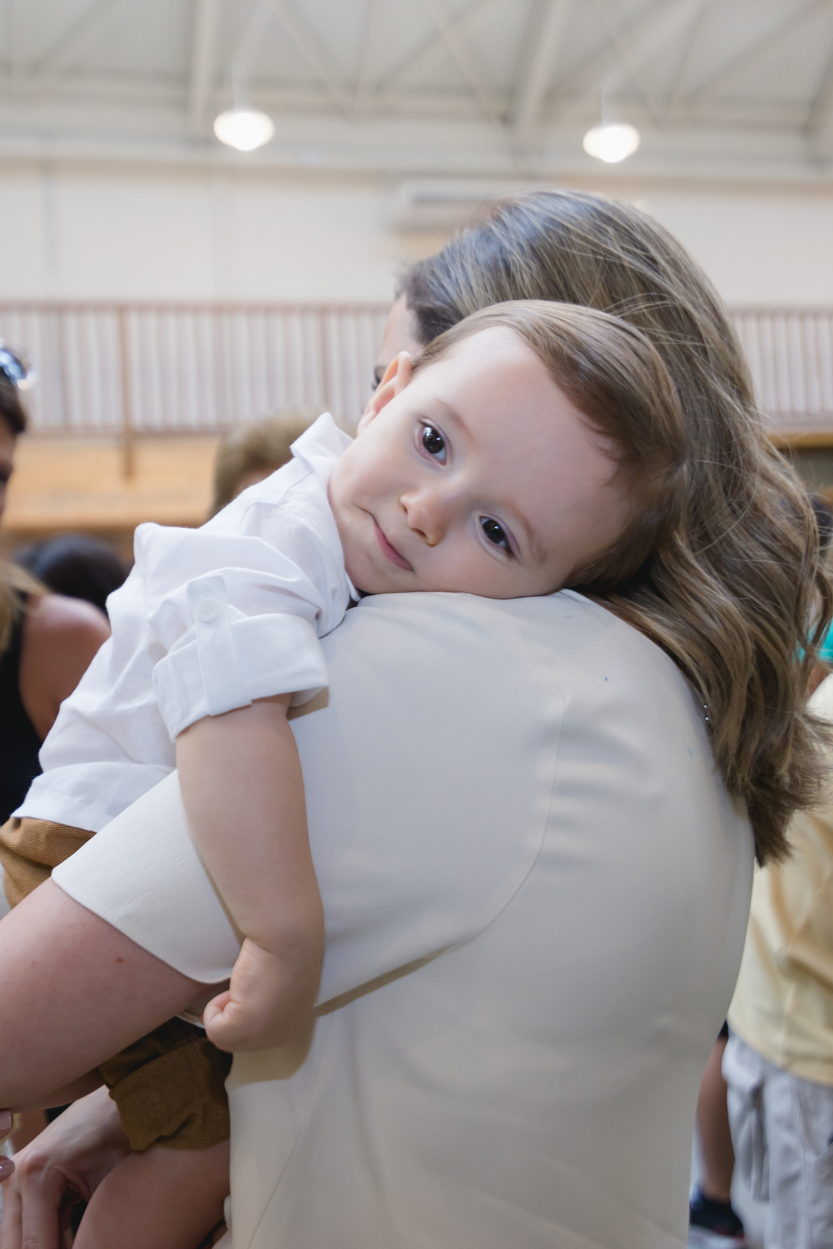 criançacansada e com sono no colo da mãe fim de festa