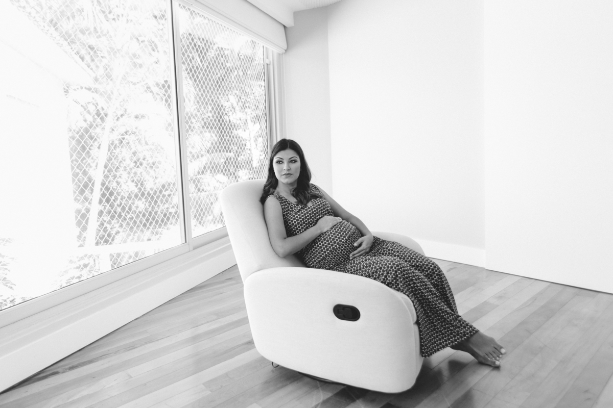 Mulher gestante sentada na poltrona com a mão na barriga