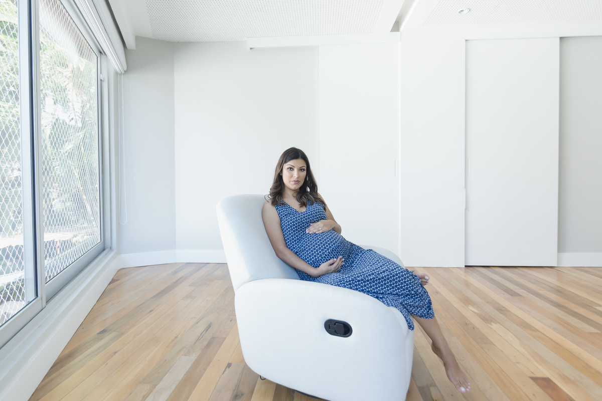 Mulher gestante sentada na poltrona com a mão na barriga