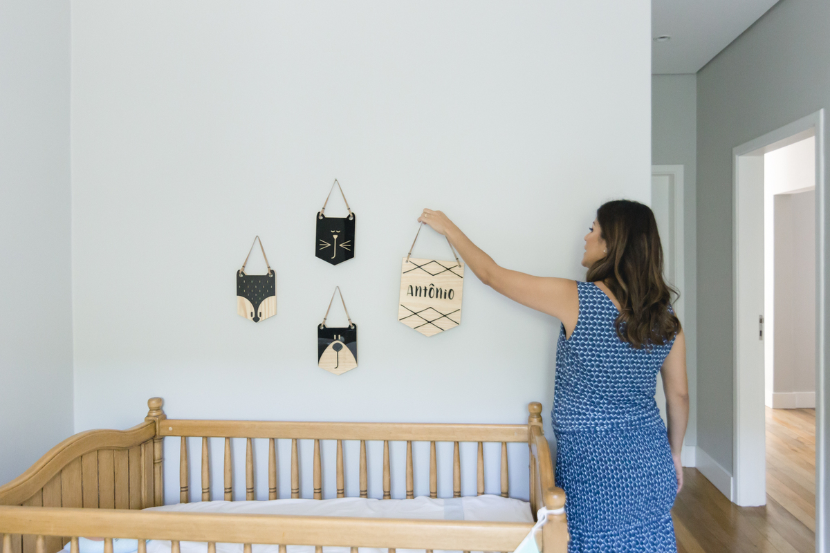 Mãe pendurando na parede flamula de madeira com o nome escrito