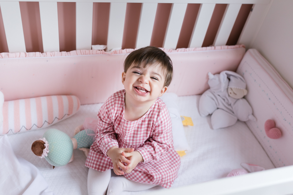 bebe sorrindo sentada dentro berço 
