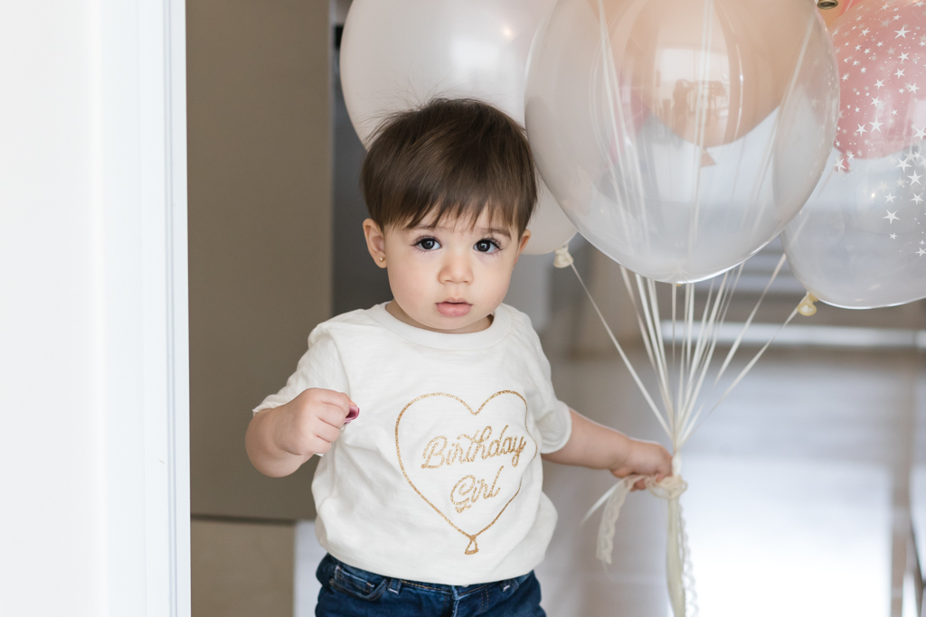 bebe segurando baloes