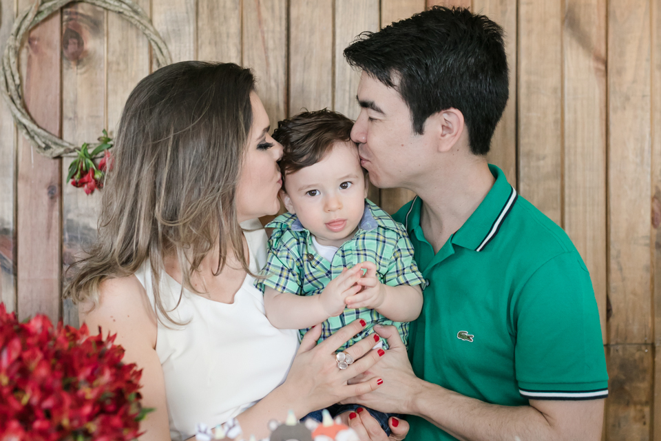 pai e mae segurando bebe no colo e beijando bebe