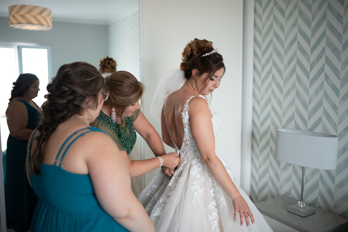mae e madrinha ajudando no vestido da noiva