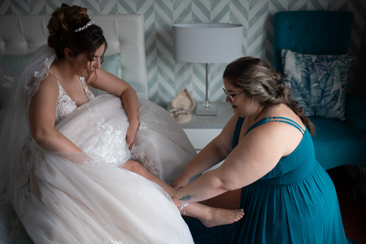 mae e madrinha ajudando no vestido da noiva