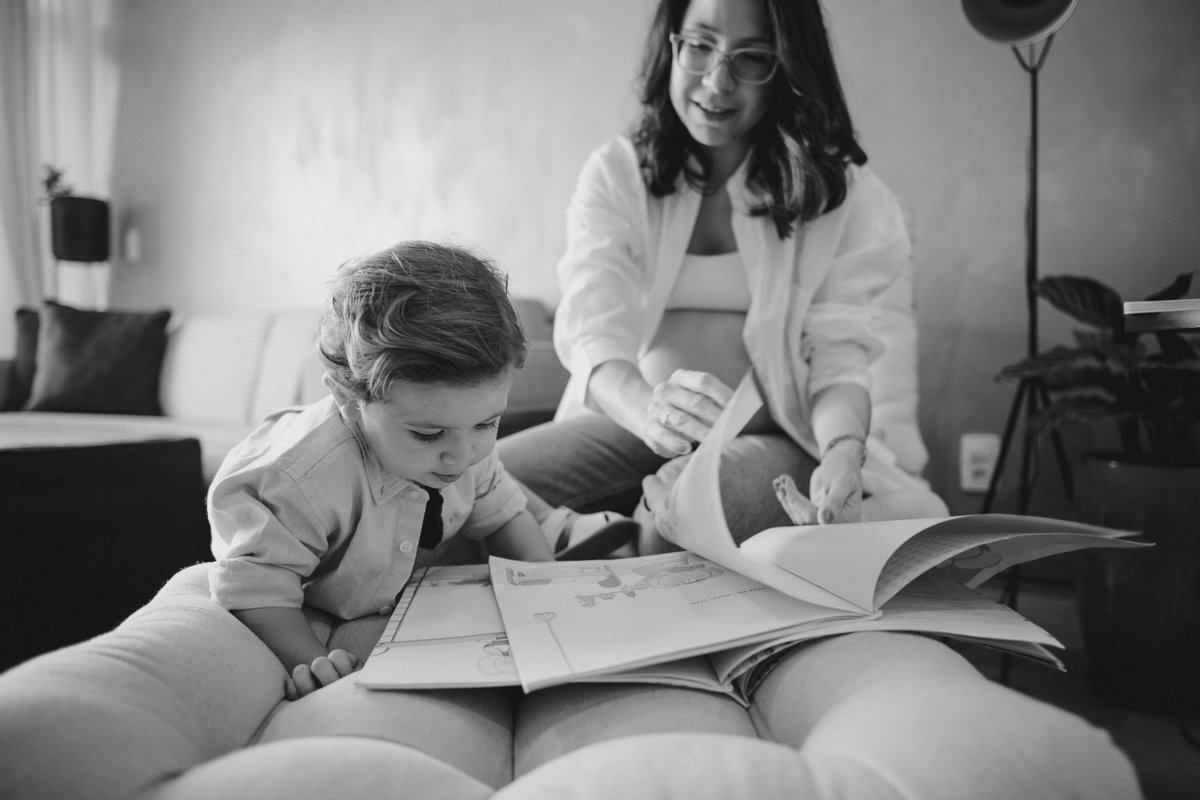 ensaio gestante em apartamento lendo livro com filho mais velho