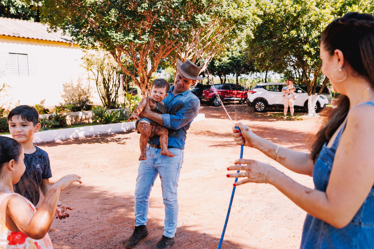 festa de 1 ano de menino tema fazendinha do bita criança de botina brincando na terra banho de mangueira