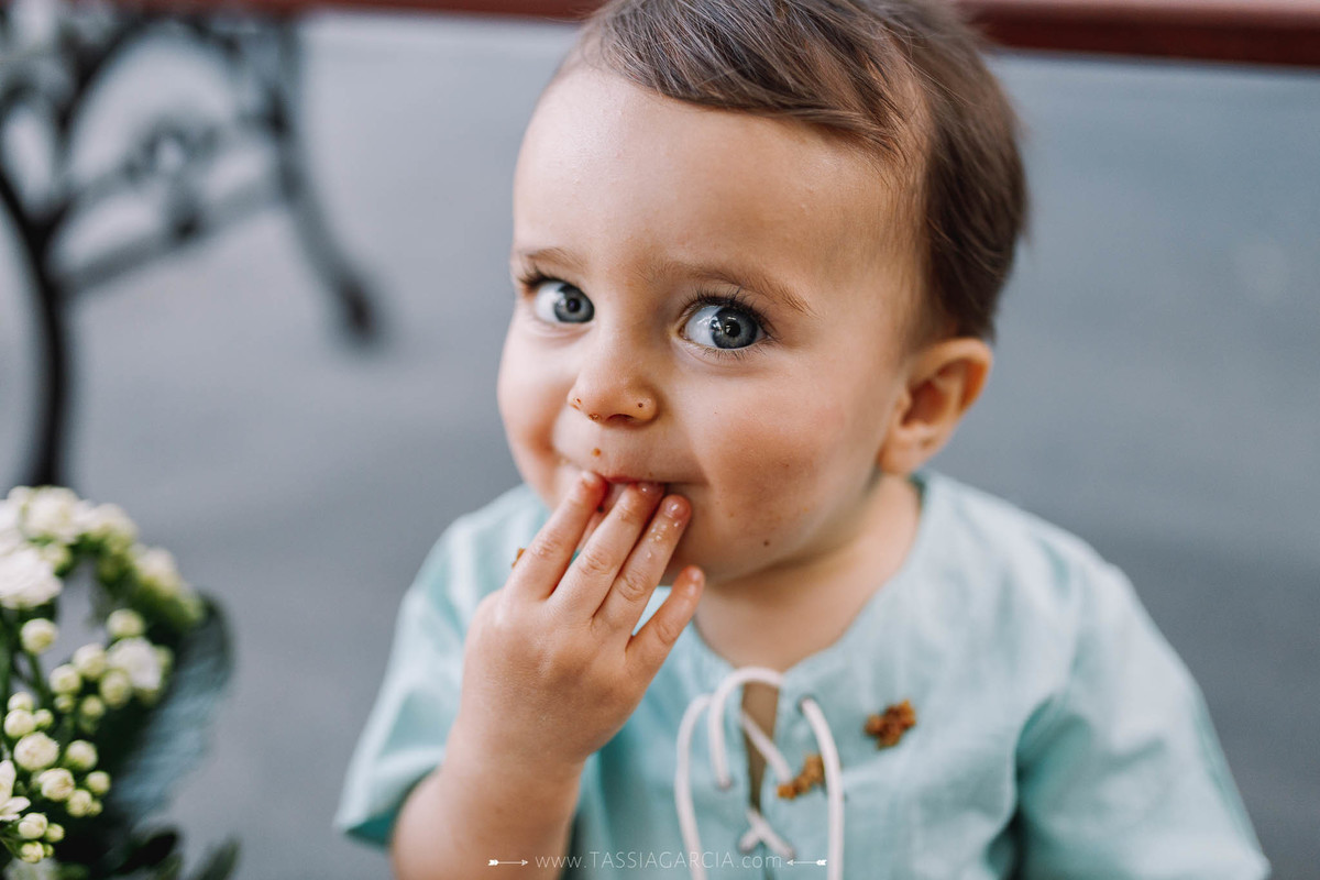 criança comendo bolo de aniversário hora do parabéns festa intimista de menino em casa 1 aninho em ribeirão preto