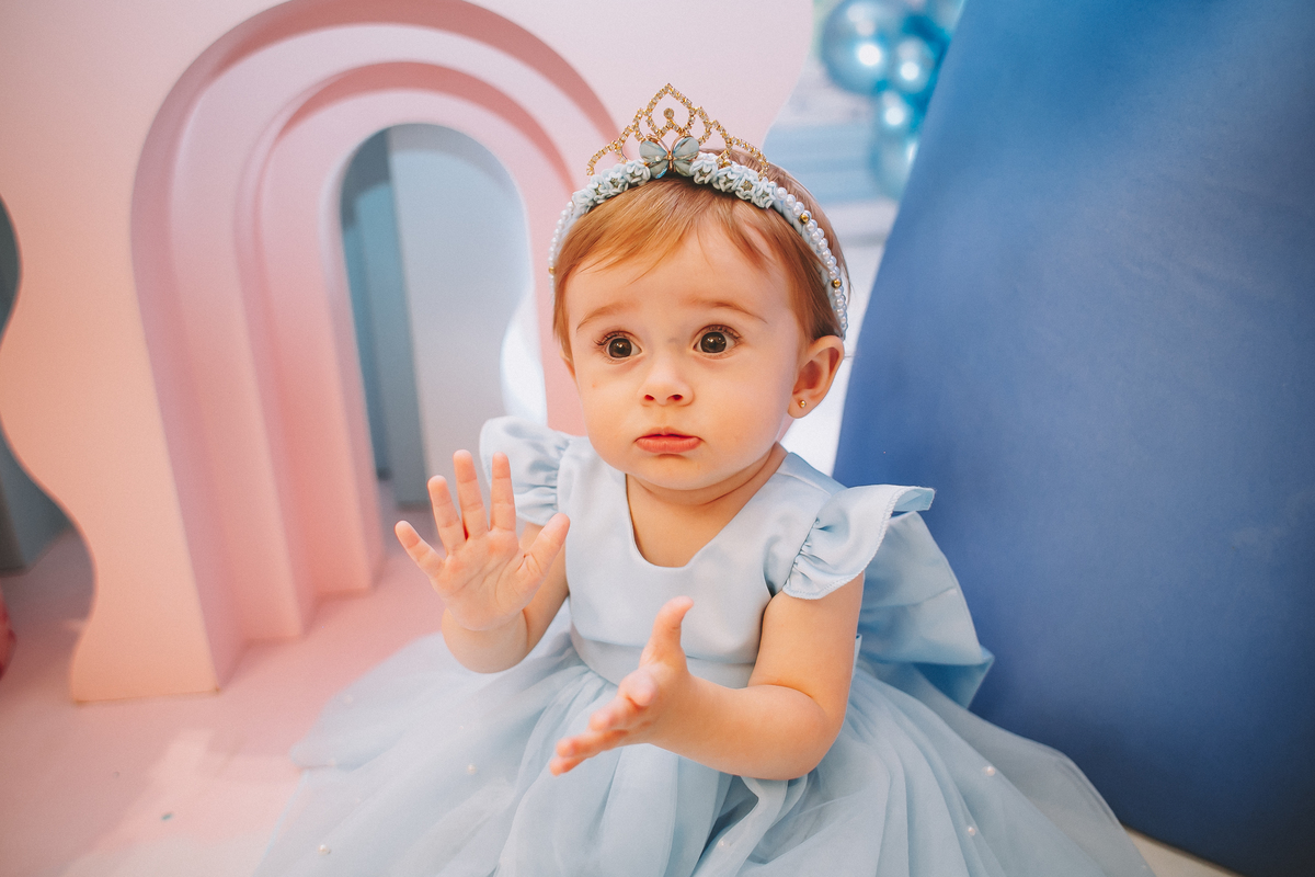 Aniversariante de 1 ano sorrindo e explorando a festa, em um momento leve e divertido