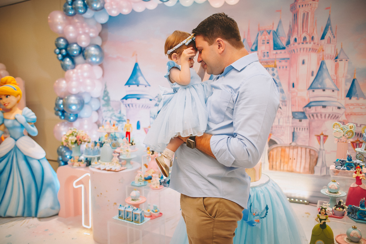 Pais brincando e aproveitando a festa com a filha no seu primeiro aniversário