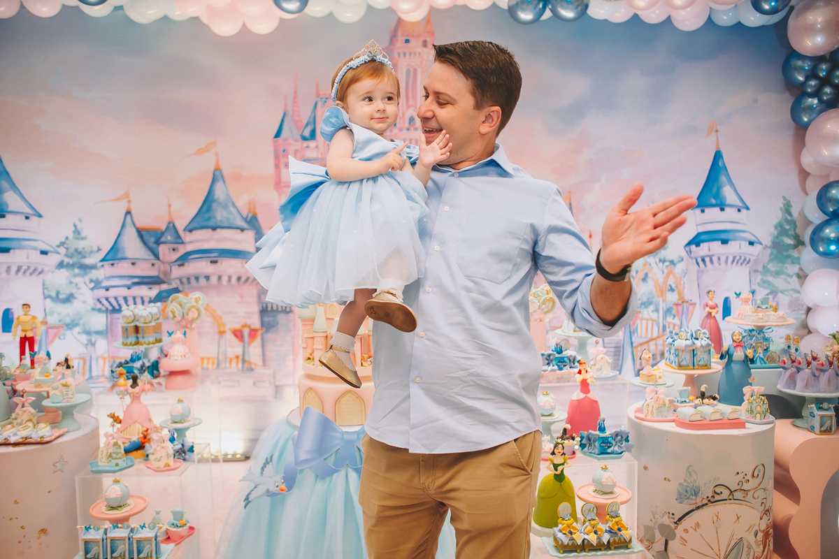 Pais brincando e aproveitando a festa com a filha no seu primeiro aniversário