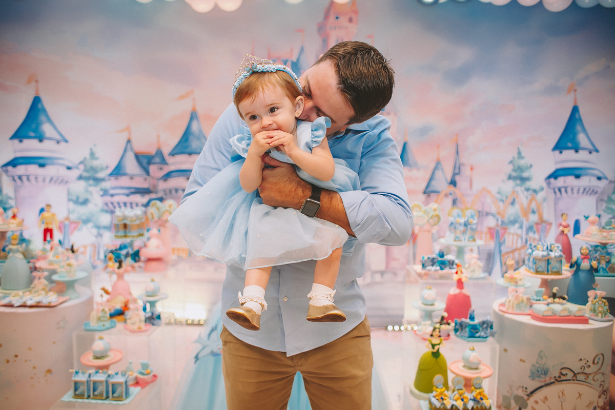 Pais brincando e aproveitando a festa com a filha no seu primeiro aniversário