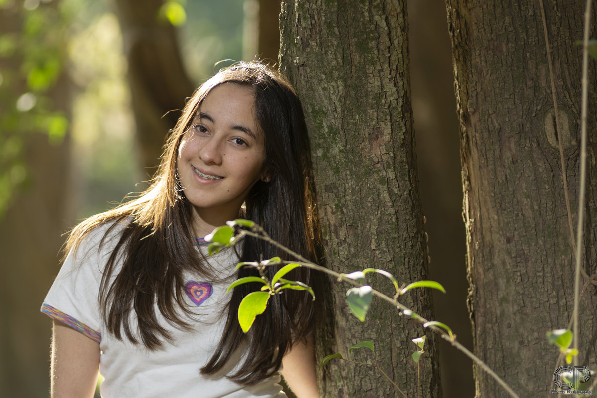 quinceañera en sesión de fotos en exteriores con fondo de arboles en un parque en rosario, 
