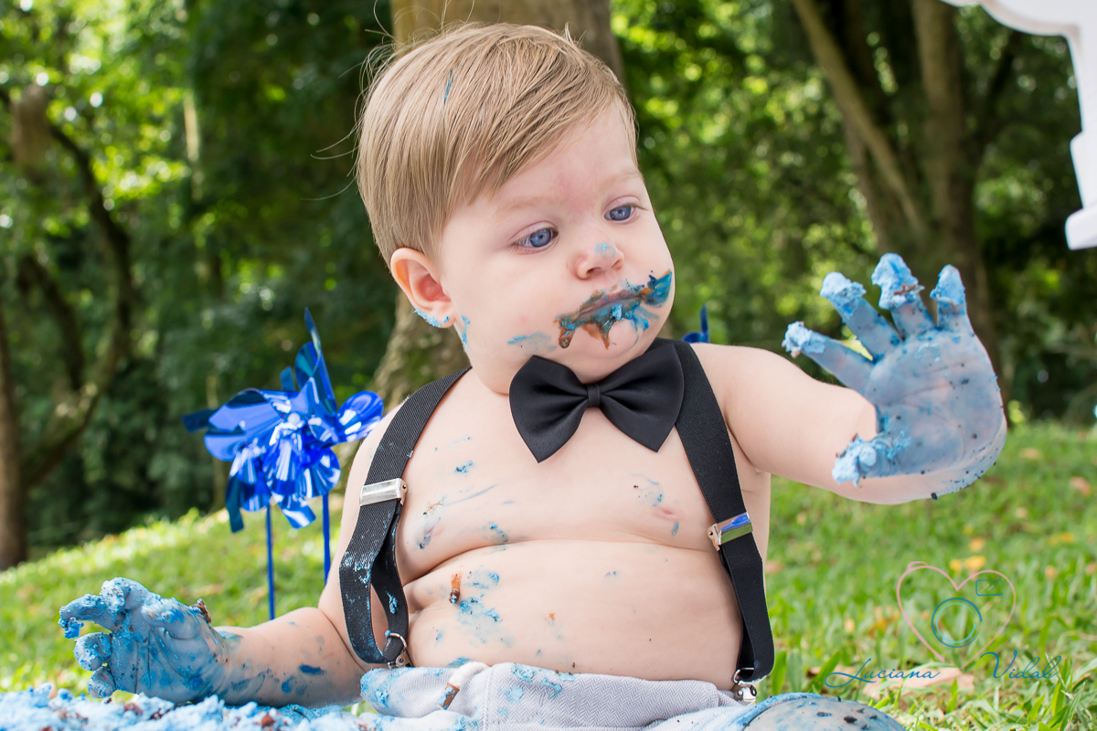 Ensaio Smash The Cake Miguel, fotografia Luciana Vidal em São Paulo,nessa foto o Miguel olha sua mãozinha cheia de bolo.