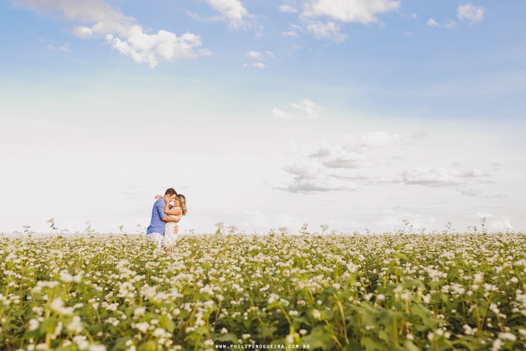 Casal de mãos dadas com céu azul em ensaio de noivos