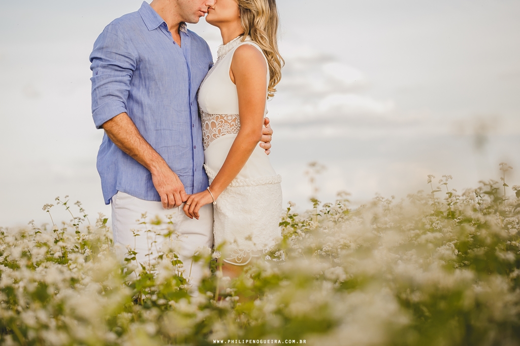 Casal de mãos dadas com céu azul em ensaio de noivos