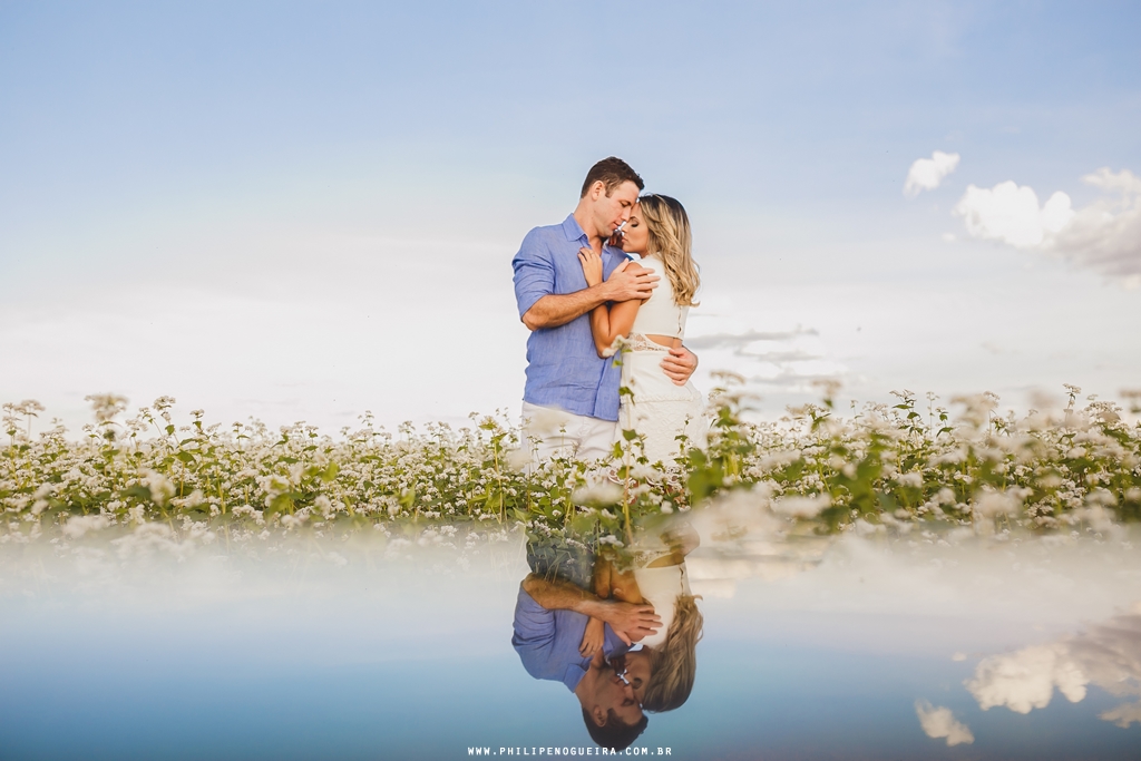 O casal no campo se abraça em fotografia com reflexo pelo fotógrafo profissional de casamento Brasília – DF