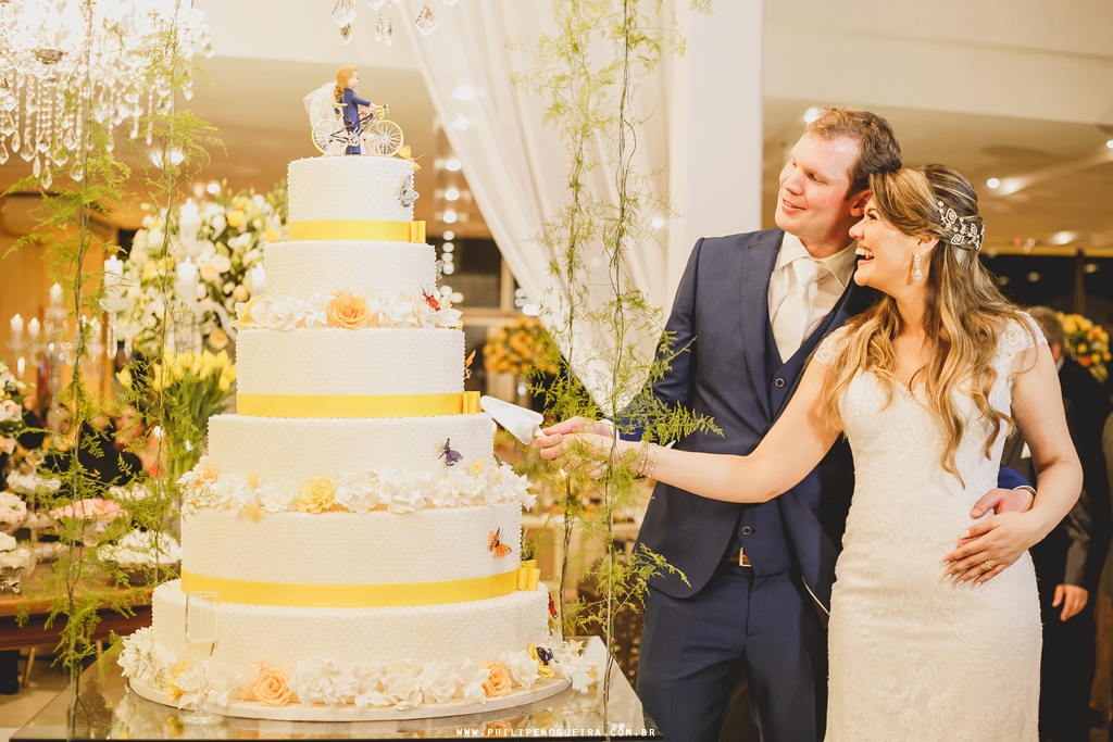 Casal na mesa do bolo em festa de casamento com decoração por Erica Magalhães no salão Porto Vitoria em fotografia profissional Brasília Df