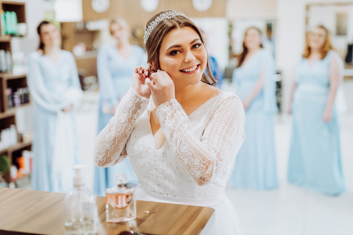 Colocando os brincos, noiva. Casamento Bianca Feller e Tiago Dauffenbach. Hair Studio C Taió, SC. Fotografia de Eduardo Pasqualini, fotógrafo de casamento, família e ensaios em Rio do Sul, Santa Catarina.