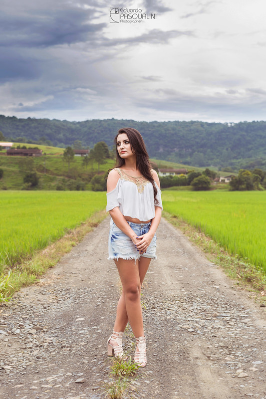 Aline fotografada em estrada de interior em meio a plantação de arroz. Fotografia de Eduardo Pasqualini, fotógrafo de casamentos e ensaios em Rio do Sul, Santa Catarina.