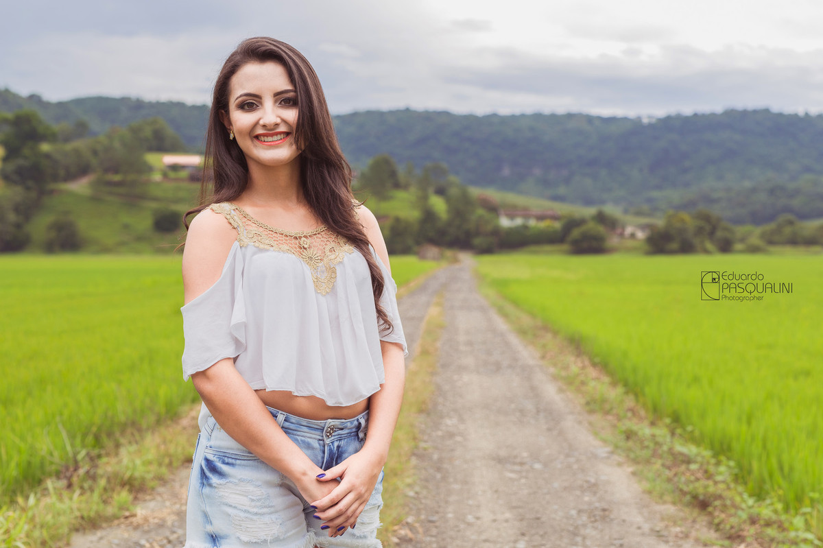 Aline em uma estrada de interior em meio a plantação de arroz. Fotografia de Eduardo Pasqualini, fotógrafo de casamentos e ensaios em Rio do Sul, Santa Catarina.