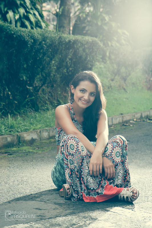 Vintage e com flare de flash, modelo Aline sentada em rua de asfalto. Fotografia de Eduardo Pasqualini, fotógrafo de casamentos e ensaios em Rio do Sul, Santa Catarina.