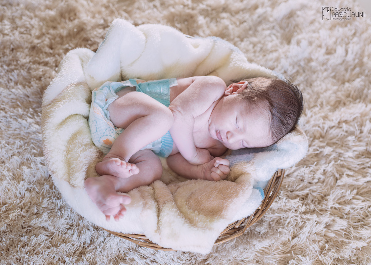 Em cesto de vime, bebê de 15 dias dorme. Fotografia de Eduardo Pasqualini, fotógrafo de casamentos e ensaios em Rio do Sul, Santa Catarina.