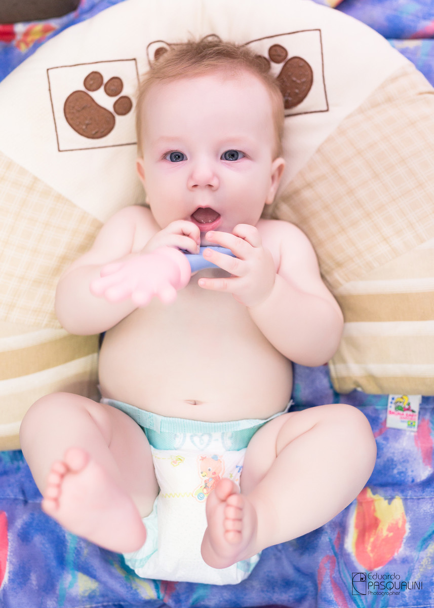 Feliz da vida, bebê a vontade brincando com brinquedo. Fotografia de Eduardo Pasqualini, fotógrafo de casamentos e ensaios em Rio do Sul, Santa Catarina.