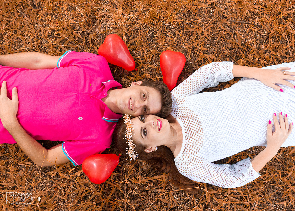 Deitados na grama com balões, casal Tamires e Cleber. Fotografia de Eduardo Pasqualini, fotógrafo de casamentos e ensaios em Rio do Sul, Santa Catarina.