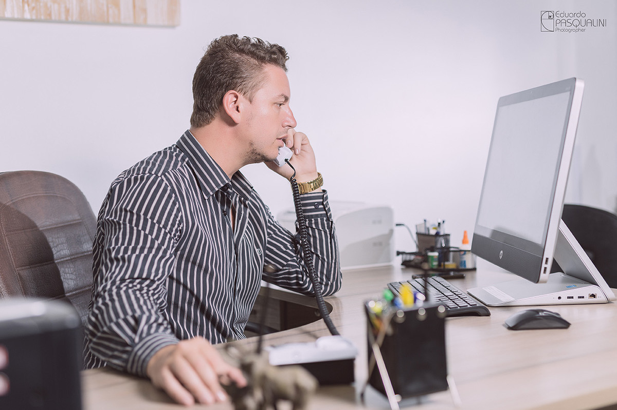 Escritório, homem falando ao telefone no escritório. Foto de Eduardo Pasqualini, fotógrafo de casamentos e ensaios em Rio do Sul, Santa Catarina.