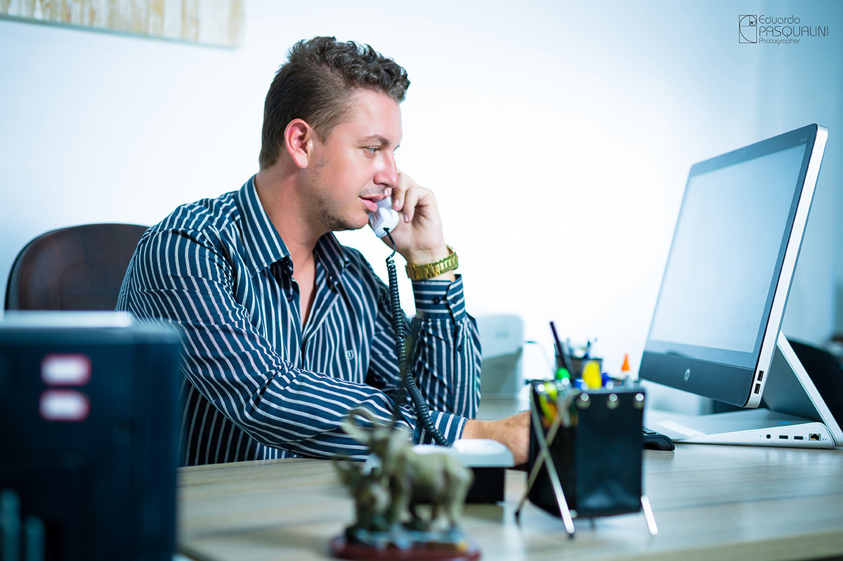Em office, homem falando ao telefone no escritório. Foto de Eduardo Pasqualini, fotógrafo de casamentos e ensaios em Rio do Sul, Santa Catarina.